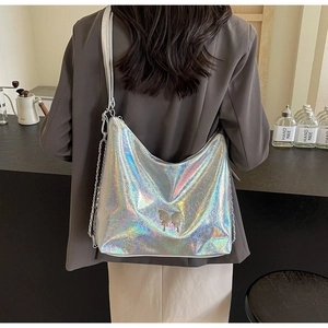 Iridescent silver crescent hobo bag with butterfly ornament worn by a model in a cafe