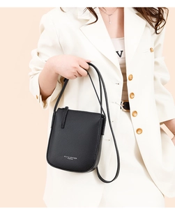 Detail of black pebble leather crossbody bag showing silver brand text and texture