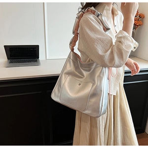 Detail of silver metallic tote bag featuring pink pleated handle and front patch pocket