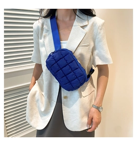 Detail shot of electric blue padded crossbody bag with quilted pattern and wide strap