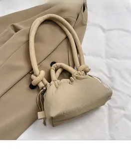 Detail of khaki padded puffy bag featuring a knotted handle and drawstring closure