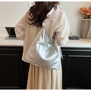 Detail of silver metallic hobo bag featuring ruffled shoulder strap and pink lining
