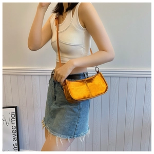 Détail du sac bandoulière en similicuir orange métallisé porté par un mannequin chic