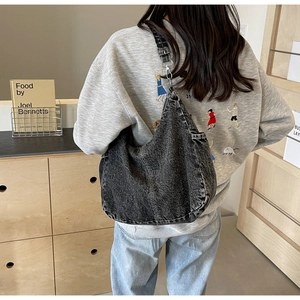Detail van grote gewassen denim draagtas met verstelbare riem en ruime opbergruimte
