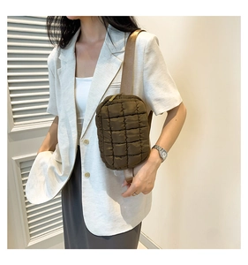 Detailed view of deep brown quilted nylon crossbody bag shown on model for size and style
