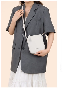 Detail of white lychee pattern leather crossbody bag with gold embossed logo text