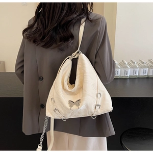 Detailed view of cream PU hobo bag featuring silver butterfly buckle and chain on shoulder