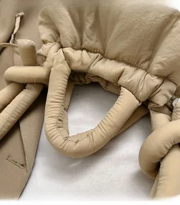 Detail view of the padded thick top handle on a beige quilted nylon crossbody bag