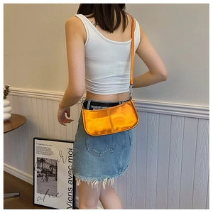 Détail d'un sac demi-lune orange métallisé en similicuir brillant avec crochets argent