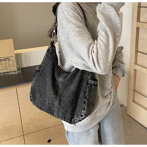 Detail van donkergrijze hobo-tas van gewassen denim met witte stiksels en zijzakken