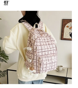 Détail du sac à dos en tweed rose avec breloque en peluche porté par un modèle