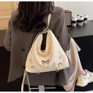 Detail of off-white hobo bag with marble texture and silver butterfly ornament on a model