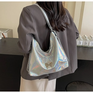 Close-up of holographic silver PU leather hobo bag with metal butterfly and chain detail