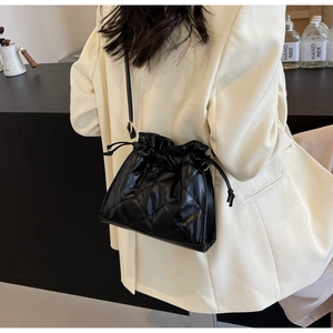 Detailed back view of a black quilted drawstring PU leather shoulder bag on a white suit
