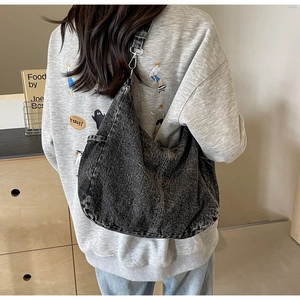 Detail van hobo tas met gewassen denim textuur en verstelbare schouderband haak