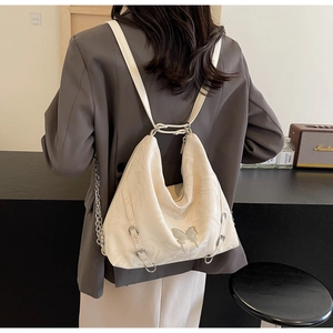 Detail of white PU leather hobo backpack with silver butterfly charm and chain accents