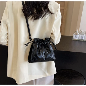 Close-up of black quilted PU leather bucket bag with drawstring and rhombus stitching
