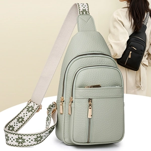 Detail view of sage green textured leather crossbody bag with patterned woven strap