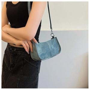 Détail du sac à bandoulière bleu en forme de croissant avec coutures et boucles argentées