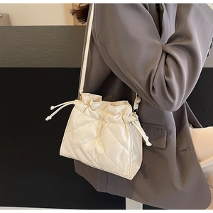 Detail of cream white quilted PU leather crossbody bag with drawstring and tassel decor