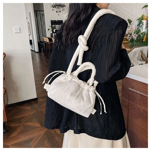 Close-up of white pleated cloud bag in leather texture with drawstring and knot strap