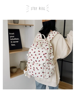 Détail d'un sac à dos en velours côtelé blanc cassé avec motif fraises et pendentif