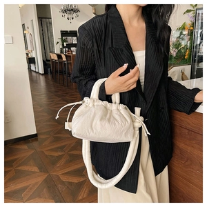 Detailed view of white pleated cloud bag with drawstring and rounded shoulder strap