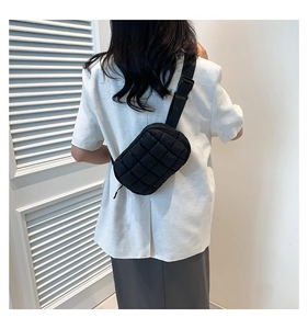 Fashionable black quilted crossbody bag shown on a model in a bright minimalist setting