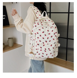 Détail du sac à dos en velours côtelé crème avec motifs fraises et pompon en peluche