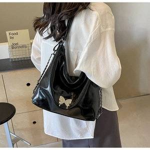 Detail of glossy black PU leather bag with silver butterfly charm and chain strap