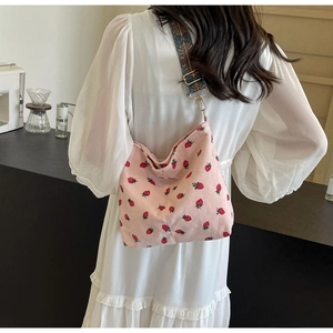 Detail of pink corduroy crossbody bag with strawberry pattern and ethnic jacquard strap