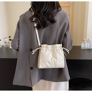 Detailed back view of a model wearing a white quilted drawstring PU leather crossbody bag