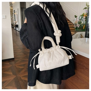 Detail of a creamy white pleated drawstring cloud bag with a stylish knotted shoulder strap