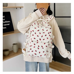 Détail du sac à dos en velours côtelé avec motif fraise et breloque ours en peluche