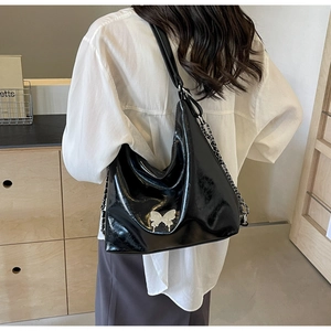 Detail of black glossy PU leather hobo bag with silver butterfly buckle and chain strap