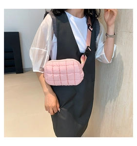 Detail of pink quilted crossbody bag featuring adjustable strap and padded fabric texture
