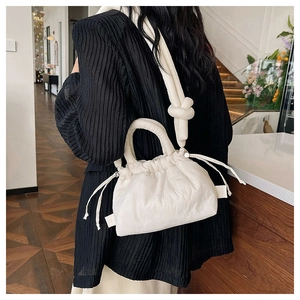 Close-up of beige drawstring puffer bag with soft ruched texture and padded shoulder strap