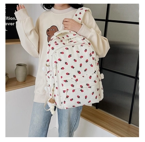 Détail d'un sac à dos en velours côtelé blanc avec imprimé fraise et pompon doux