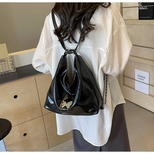 Detail of black glossy PU leather backpack featuring a silver butterfly buckle and chain strap