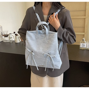 Detail of light blue PU backpack featuring pleat texture and elegant bow ribbons