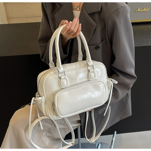 Detail view of cream white glossy PU leather backpack showing fine texture and front pocket