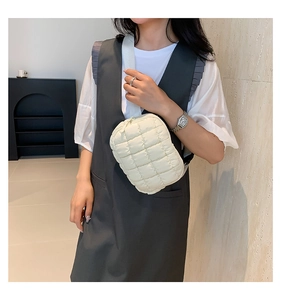 Close-up of white quilted puffer crossbody bag with nylon texture and adjustable strap