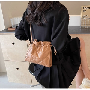 Detail of caramel brown quilted PU leather bucket bag with drawstring closure and strap