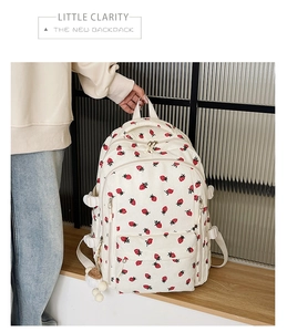 Détail d'un sac à dos en velours côtelé crème avec imprimé fraise et pompon doux