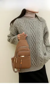 Brown lychee leather crossbody bag with jacquard strap and three gold zippers on model