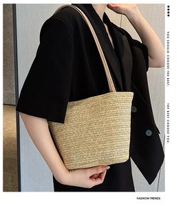 Detail of hand-woven straw tote bag featuring a beige herringbone pattern and thin strap