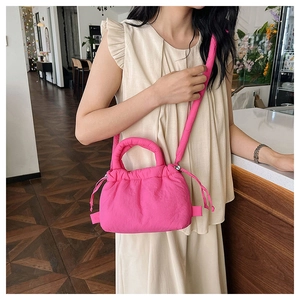 Detailed view of hot pink puffy drawstring crossbody bag with quilted texture