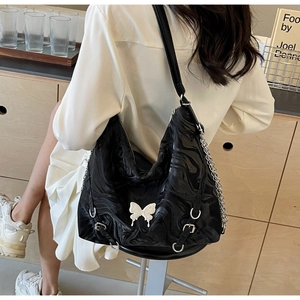 Detail of black hobo bag with marble texture and a white 3D butterfly pendant