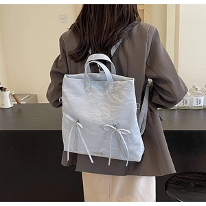 Detail of light blue PU leather backpack featuring soft crinkled texture and ribbon bows
