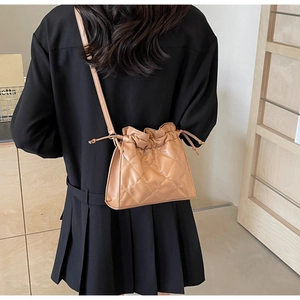 Caramel quilted PU leather drawstring crossbody bag shown on a model in a minimal setting